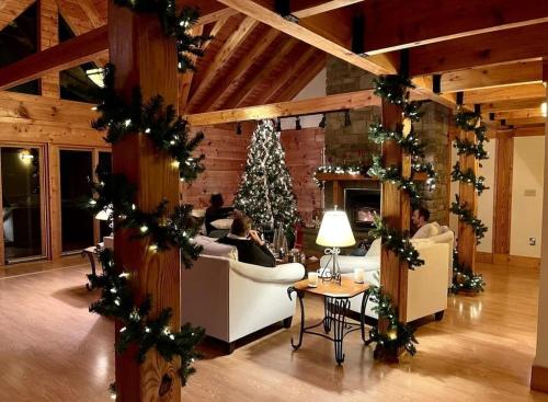 a room with a christmas tree and people sitting in chairs at Misty Mountains Lodge in Ronceverte