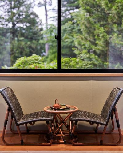 two chairs and a table in front of a window at Ajisai Onsen Ryokan - Award Winning Private Open Air Onsen in Hakone