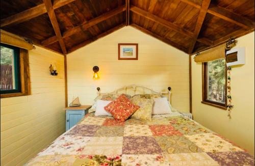 a bedroom with a bed in a room with wooden ceilings at Rustic cabin with hot tub - Homewood Forest Retreat in Alexandra