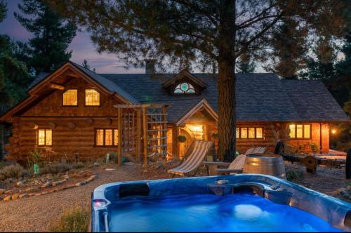 a log house with a hot tub in front of it at Rustic cabin with hot tub - Homewood Forest Retreat in Alexandra