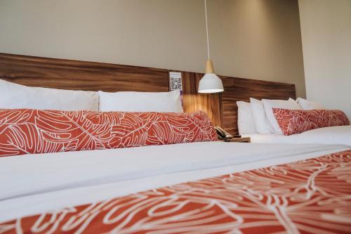 a hotel room with two beds with red and white sheets at Novotel Medellin El Tesoro in Medellín
