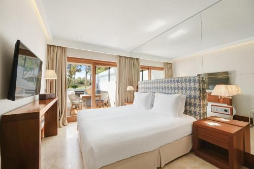 a hotel room with a bed and a desk and a television at Gecko Hotel & Beach Club in Playa Migjorn