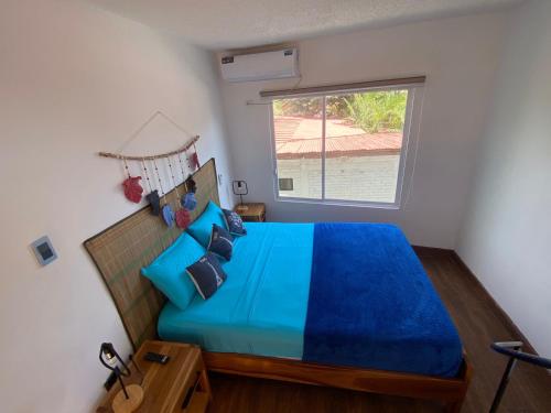 a bedroom with a blue bed with a window at Verano Azul Loft in Puerto López
