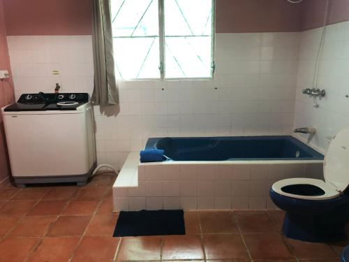 y baño con bañera azul y aseo. en Casa El Bonito Descanso, en San Vito