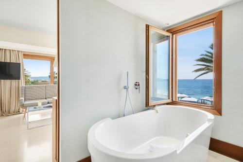 a white bath tub in a room with a window at Gecko Hotel & Beach Club in Playa Migjorn