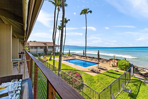 a balcony with a view of a swimming pool and the ocean at Hale Kai 220 in Kahana