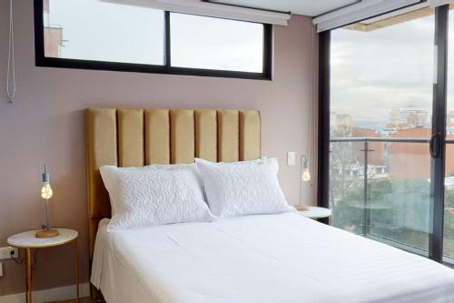a bedroom with a white bed with a large window at 902 Cityscape Loft in Bogotá