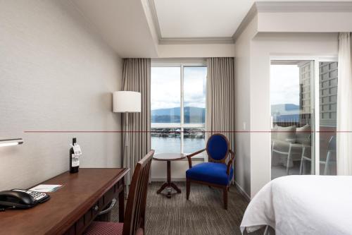 a hotel room with a desk and a bed and a window at Manteo at Eldorado Resort in Kelowna