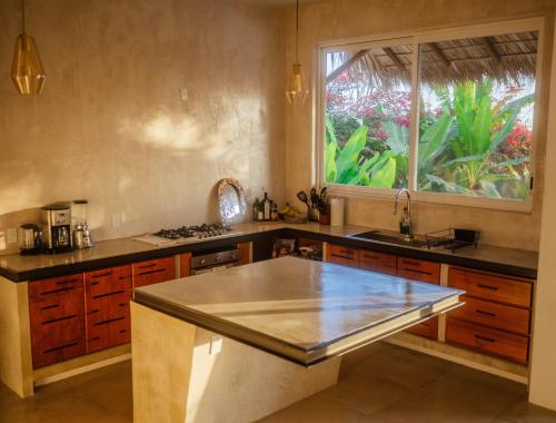 uma grande cozinha com um lavatório e uma janela em Casa La Bomba em Puerto Escondido