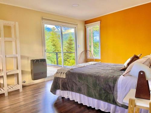 1 dormitorio con cama y ventana grande en Balcón al Piltri Casa de Montaña en El Bolsón
