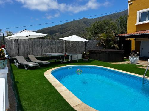 una piscina en un patio con sillas y sombrillas en TERRAZITA en Tijarafe