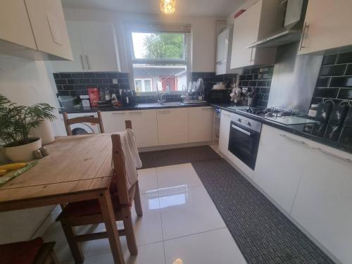 a kitchen with a wooden table and a table and a window at Private Double Room in London in Streatham Vale