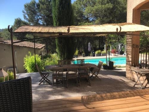 eine Terrasse mit einem Tisch, Stühlen und einem Pool in der Unterkunft Chambres d'hôtes La Manola in Rognes