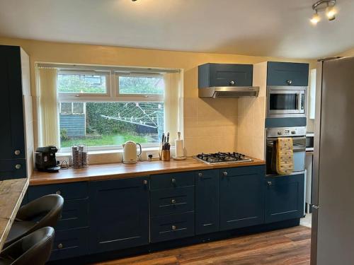 a large kitchen with blue cabinets and a window at Entire Home in Middlesbrough