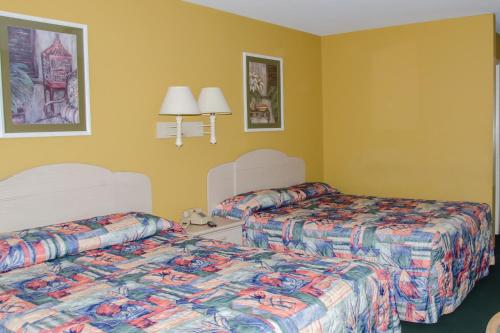two beds in a hotel room with yellow walls at Key West Inn - Childersburg in Childersburg
