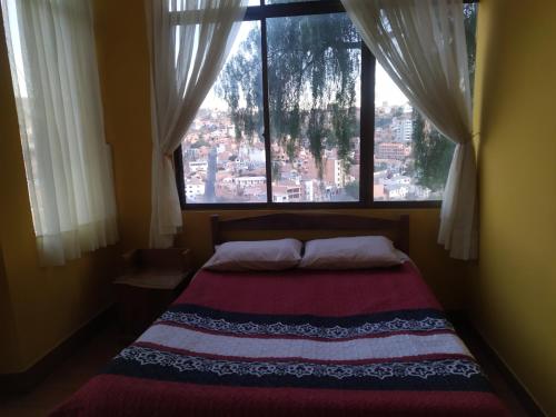 a bed in a room with a large window at Hostal Alejandra in Sucre