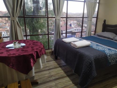 a room with two beds and a table and a window at Hostal Alejandra in Sucre