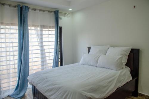 a bed with white sheets and blue curtains in a bedroom at Nsunge Nsunge Farm and Natural Resort in Lusaka