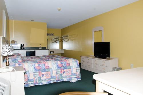 a hotel room with a bed and a tv at Key West Inn - Childersburg in Childersburg