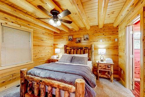 Dormitorio en cabaña de madera con cama y ventilador de techo en Deep Creek Mountain Retreat, en McHenry