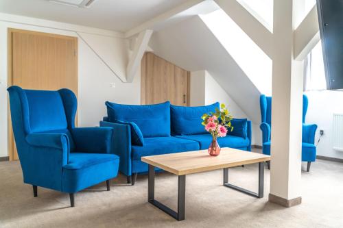 a living room with blue chairs and a table at Hotel Alpin in Szczyrk