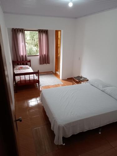 a bedroom with a bed and a chair and a window at POUSADA DA PONTE IBIRAQUERA in Imbituba