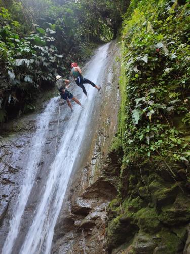 two people on a dirt road next to a waterfall at Glamping eco descanso la vega Nocaima in Nocaima