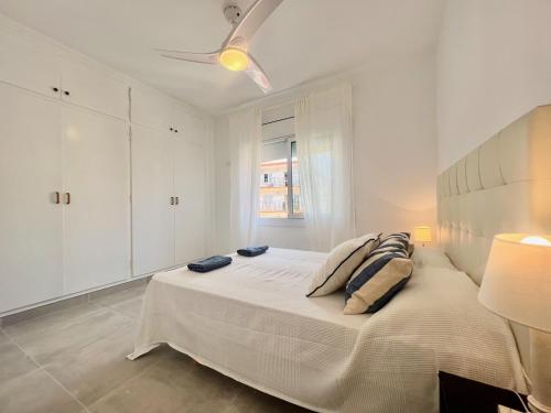 a white bedroom with a large bed and a ceiling fan at GOLDEN COAST CALAFELL 2 in El Vendrell
