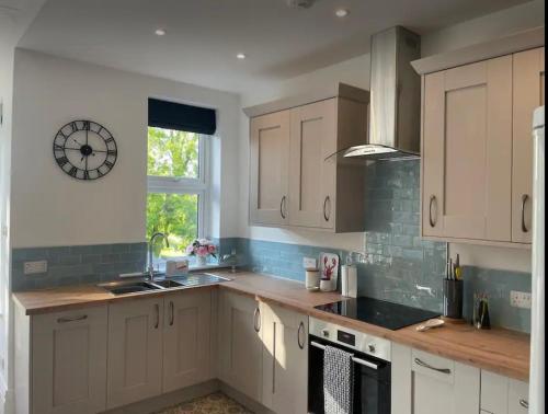 a kitchen with white cabinets and a clock on the wall at Beautiful apartment in Harrogate, North Yorkshire in Harrogate