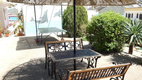 a table and two benches under an umbrella at Milos Apartments in Elounda