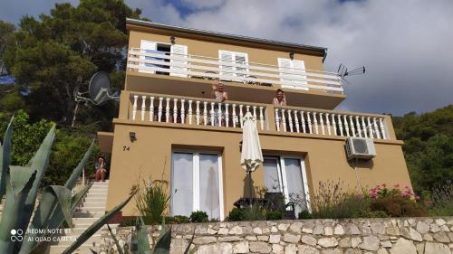 a house with two women sitting on a balcony at Apartments and rooms with WiFi Sobra, Mljet - 18465 in Babino Polje