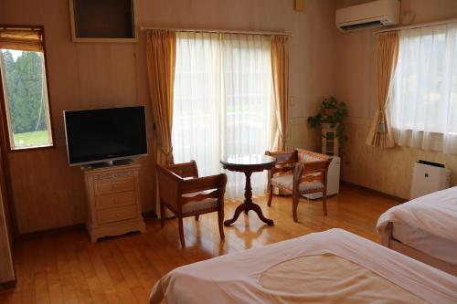 a bedroom with a tv and a table and chairs at Shikisai no Sato Manyu in Kirishima