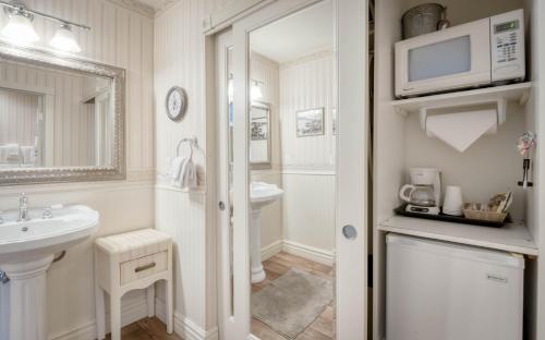 a white bathroom with a sink and a microwave at Bayfront History - Anchor Pier Lodge in Newport
