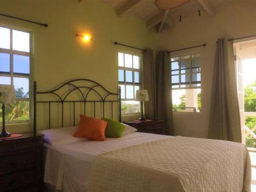 a bedroom with a bed with white sheets and windows at Vacation Home with Private Pool in Jolly Harbour