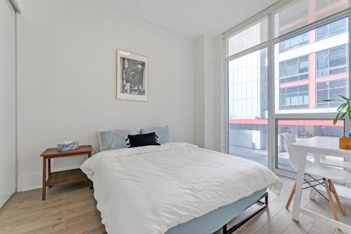 um quarto branco com uma cama, uma secretária e uma janela em Luxury 2BR Apt-CN View-Free Parking-Roof Top Pool em Toronto