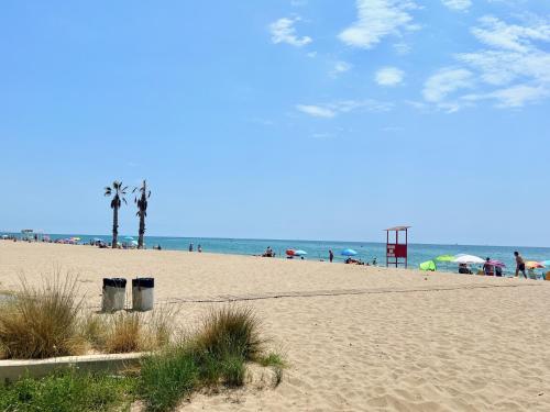 a beach with palm trees and people on the beach at GOLDEN COAST CALAFELL 2 in El Vendrell
