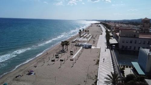 a beach with chairs and palm trees and the ocean at GOLDEN COAST CALAFELL 2 in El Vendrell