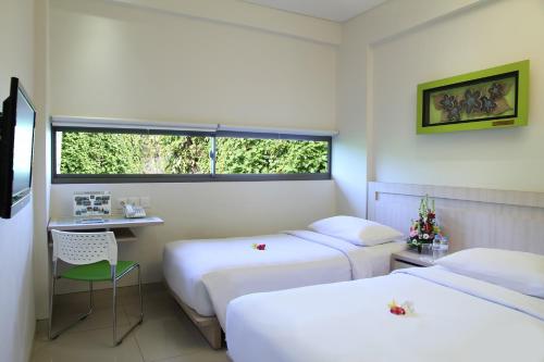 een hotelkamer met 2 bedden en een raam bij J Hotel Kuta in Kuta