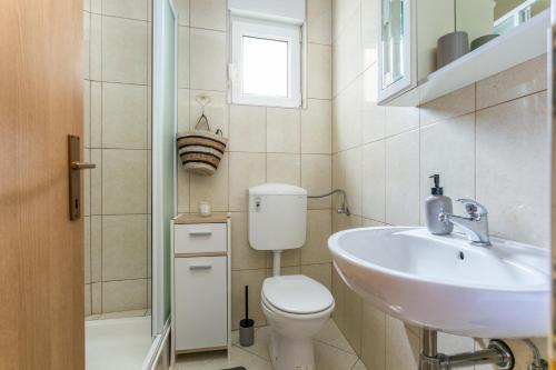 y baño con aseo, lavabo y ducha. en Apartments with a parking space Kastel Stafilic, Kastela - 20926, en Kaštela
