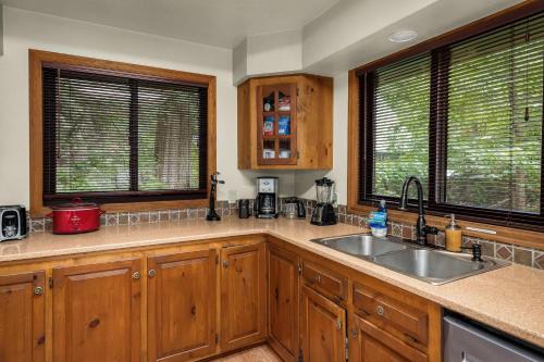 a kitchen with wooden cabinets and a sink and two windows at Sky Serenity in Skykomish