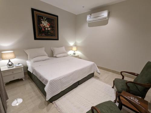 a bedroom with a white bed and a chair at Ain Arees in Al Madinah