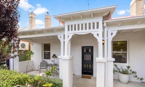 a white house with a front door and a porch at Roseland Cottage - CBD Heritage in Orange