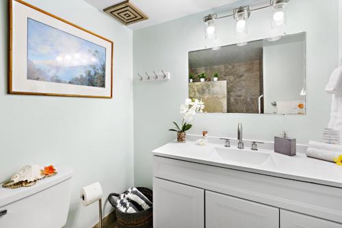 a white bathroom with a sink and a mirror at Kahana Villa F407 in Kahana