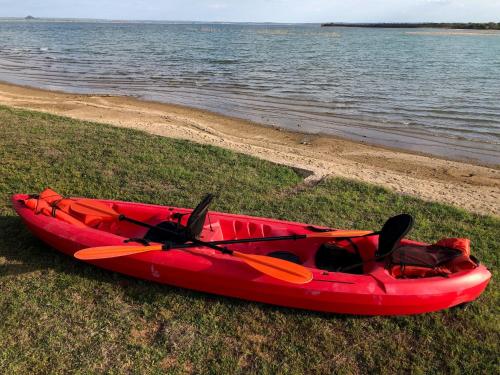 a red kayak sitting on the grass next to the water at Oasis Lake Buchanan in Bluffton