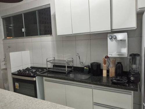 uma cozinha com armários brancos e uma bancada em Apartamento setor Bueno em Goiânia