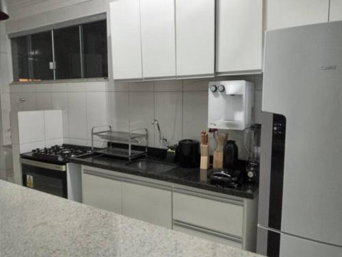 uma cozinha com armários brancos e uma bancada em Apartamento setor Bueno em Goiânia