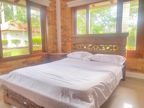 La mejor casa campestre a 25 min de Villavicencio في فيلافيسينسيو: غرفة نوم بسرير وملاءات بيضاء ونوافذ