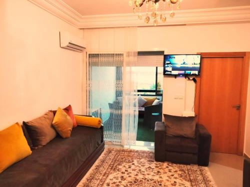 uma sala de estar com um sofá e uma televisão em Marina Golf Asilah em Asilah