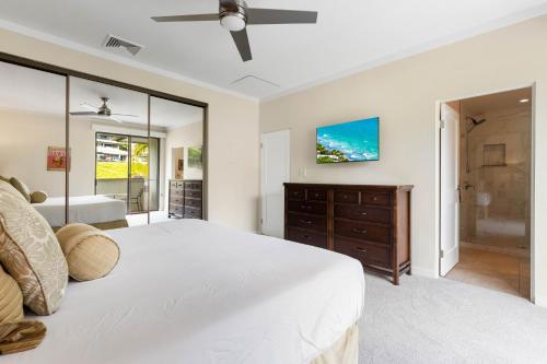 a bedroom with a large white bed and a tv at Kapalua Golf Villa 18V4 in Kahana