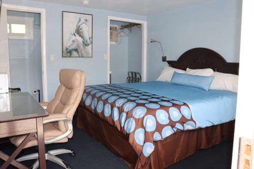 a bedroom with a bed and a desk and a chair at Hitching Post Motel 